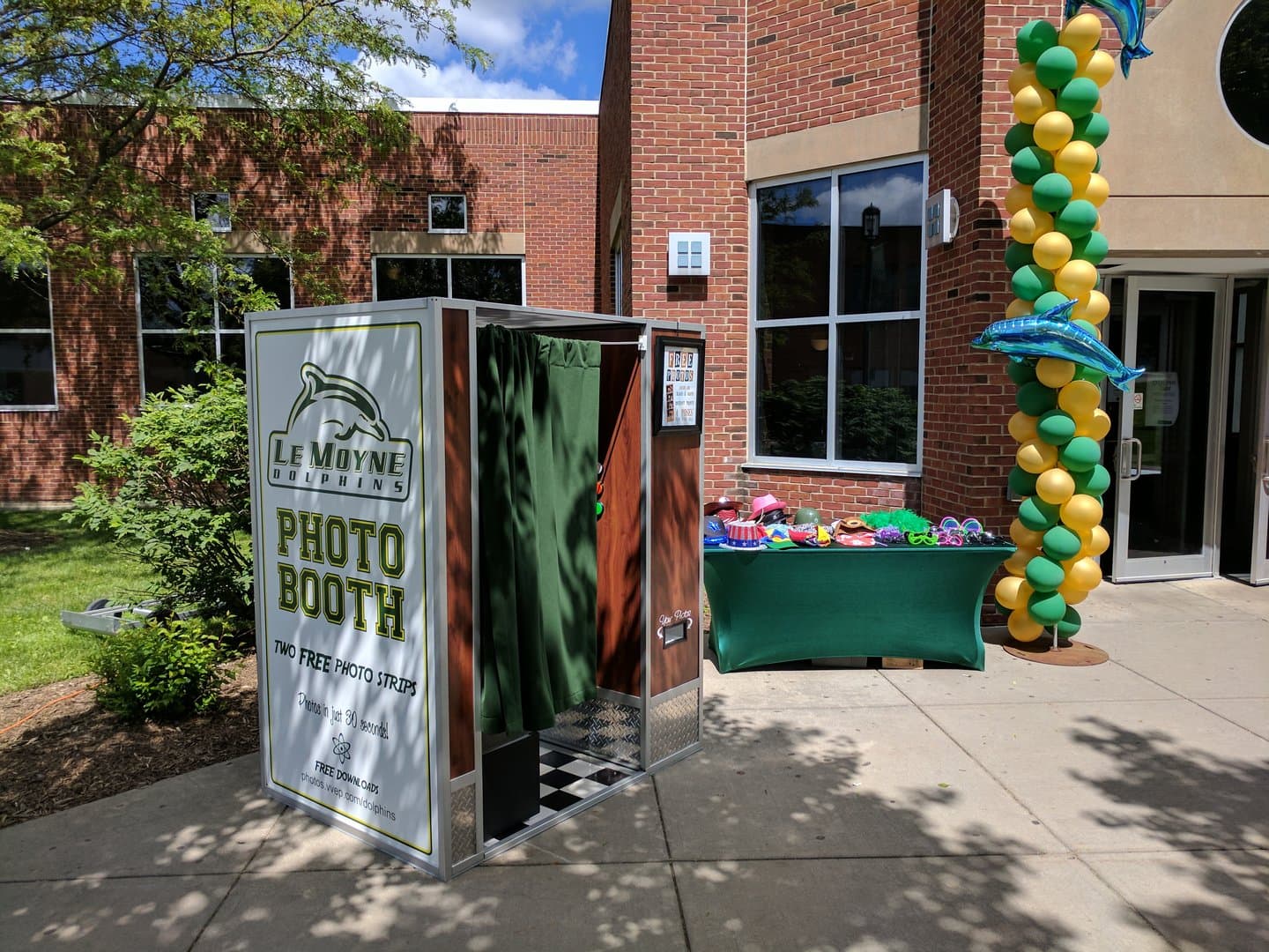 Le Moyne Dolphins branded photo booth set up outdoors beside a loaded prop table