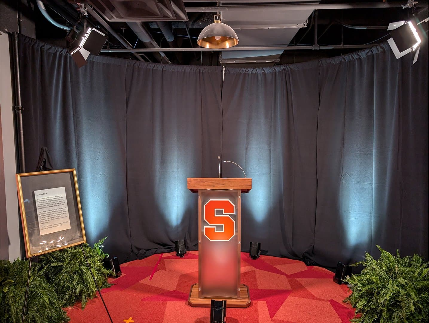 A clean small-event stage with a custom podium, drape, and focused lighting