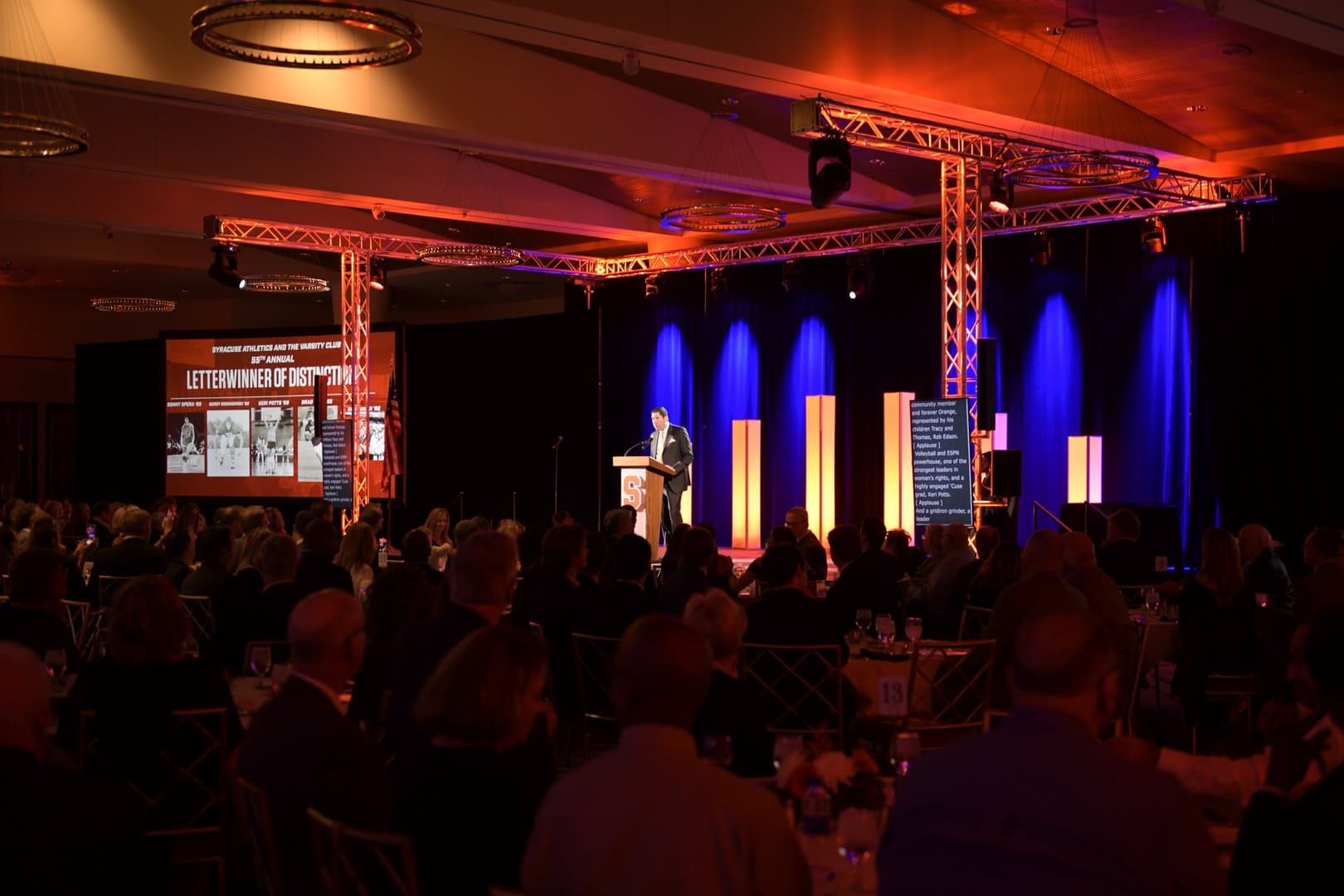 Formal university ceremony with stage lighting, projection, and a seated audience