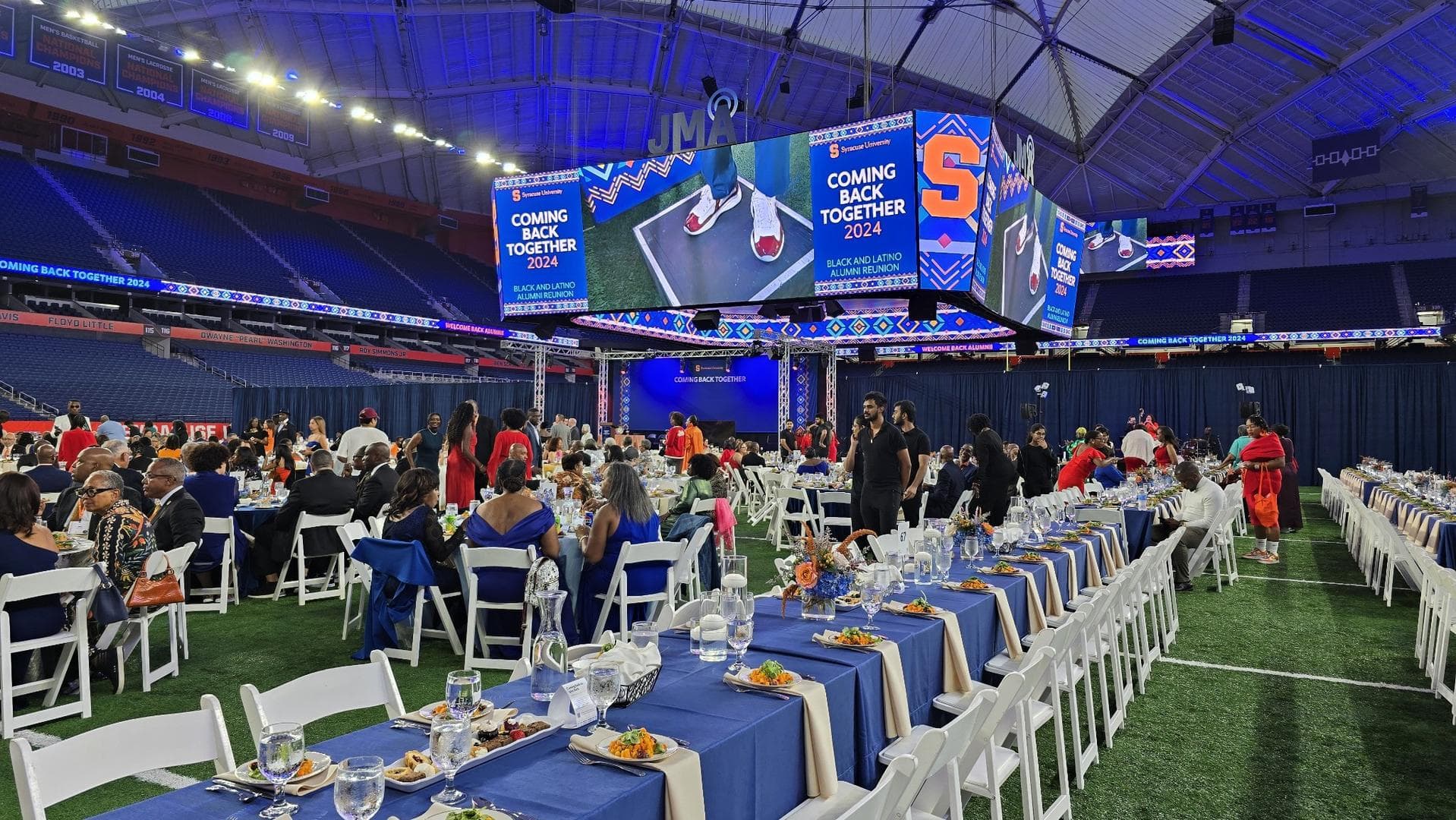 Guests dining beneath arena video boards at a university alumni reunion
